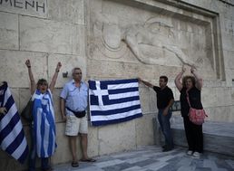 Grécki demonštranti proti úsporným opatreniam držia grécke zástavy počas protestného zhromaždenia proti vládnej dohode s veriteľmi pred hrobom neznámeho vojaka v Aténach